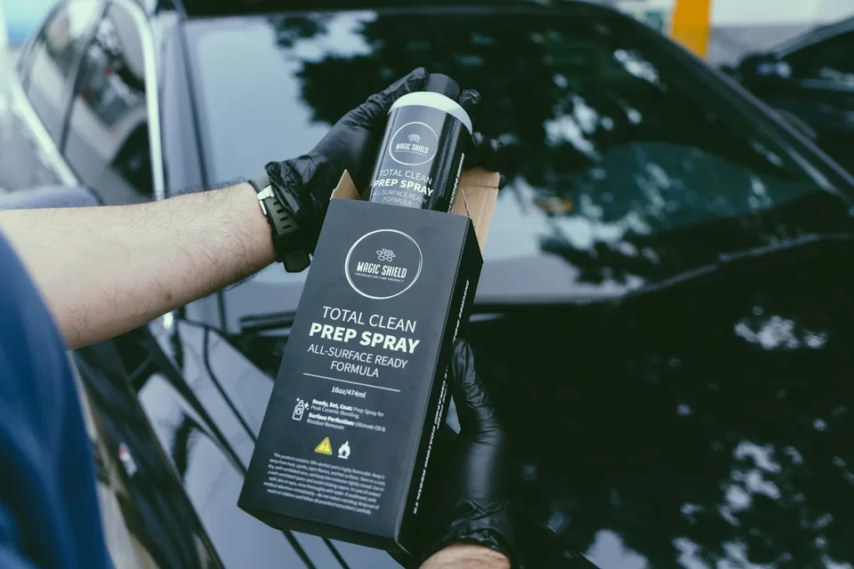 Detailer holding Magic Shield Prep Spray beside a polished vehicle