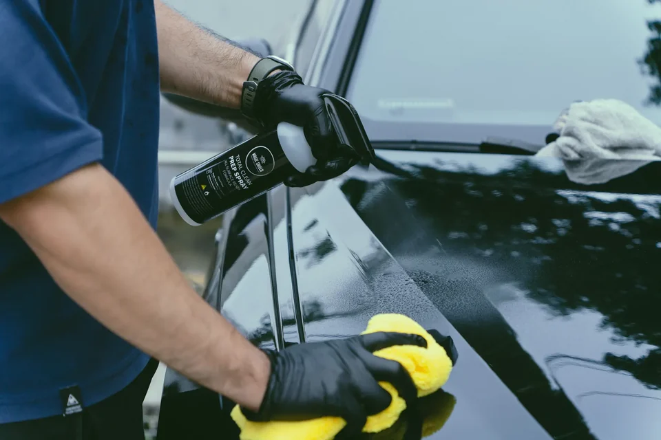 Detailer wiping automotive glass and paint with a clean microfiber towel